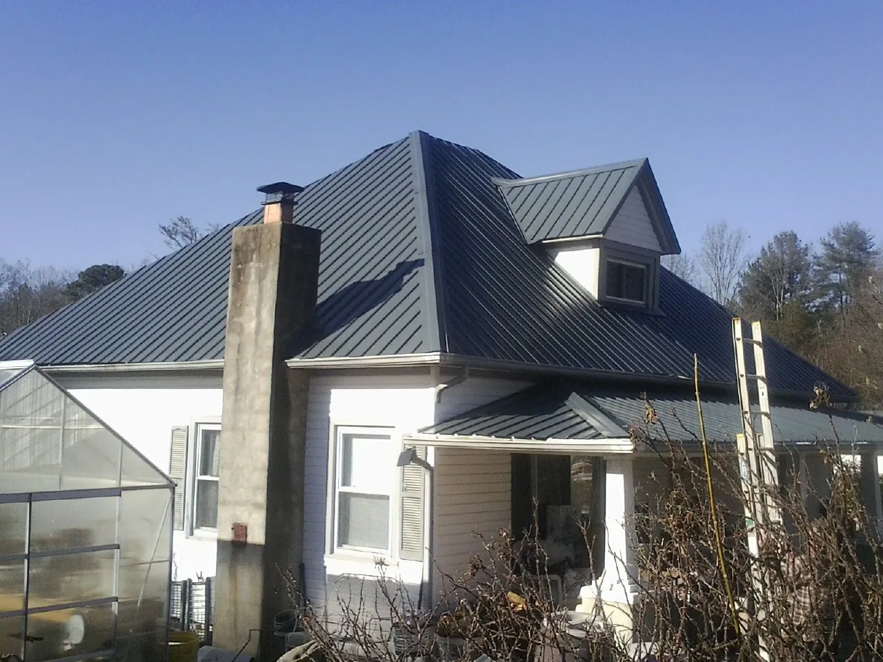Dark blue standing seam metal roof on a white farmhouse with dormer — Slate & Tile Roof Repair by Roofing Brothers in Packwood
