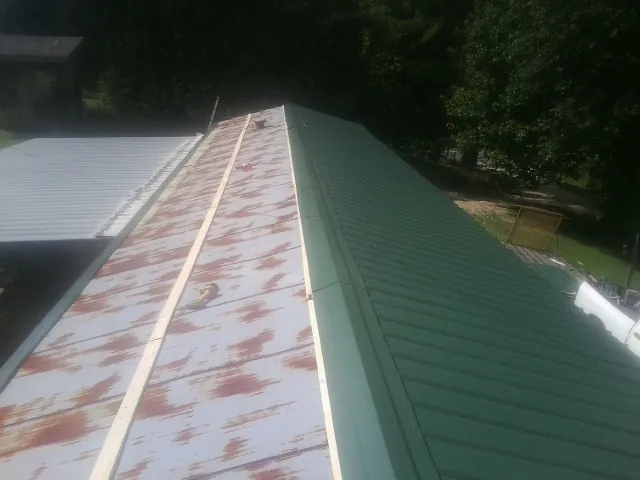 Old rusted panels beside newly installed green metal roofing — Wind Damage Roof Repair by Roofing Brothers in Packwood
