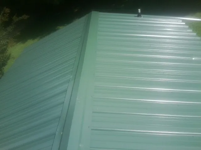 New green metal panels meeting at the ridge of a roof — Flat Roof Repair work by our crew in Packwood