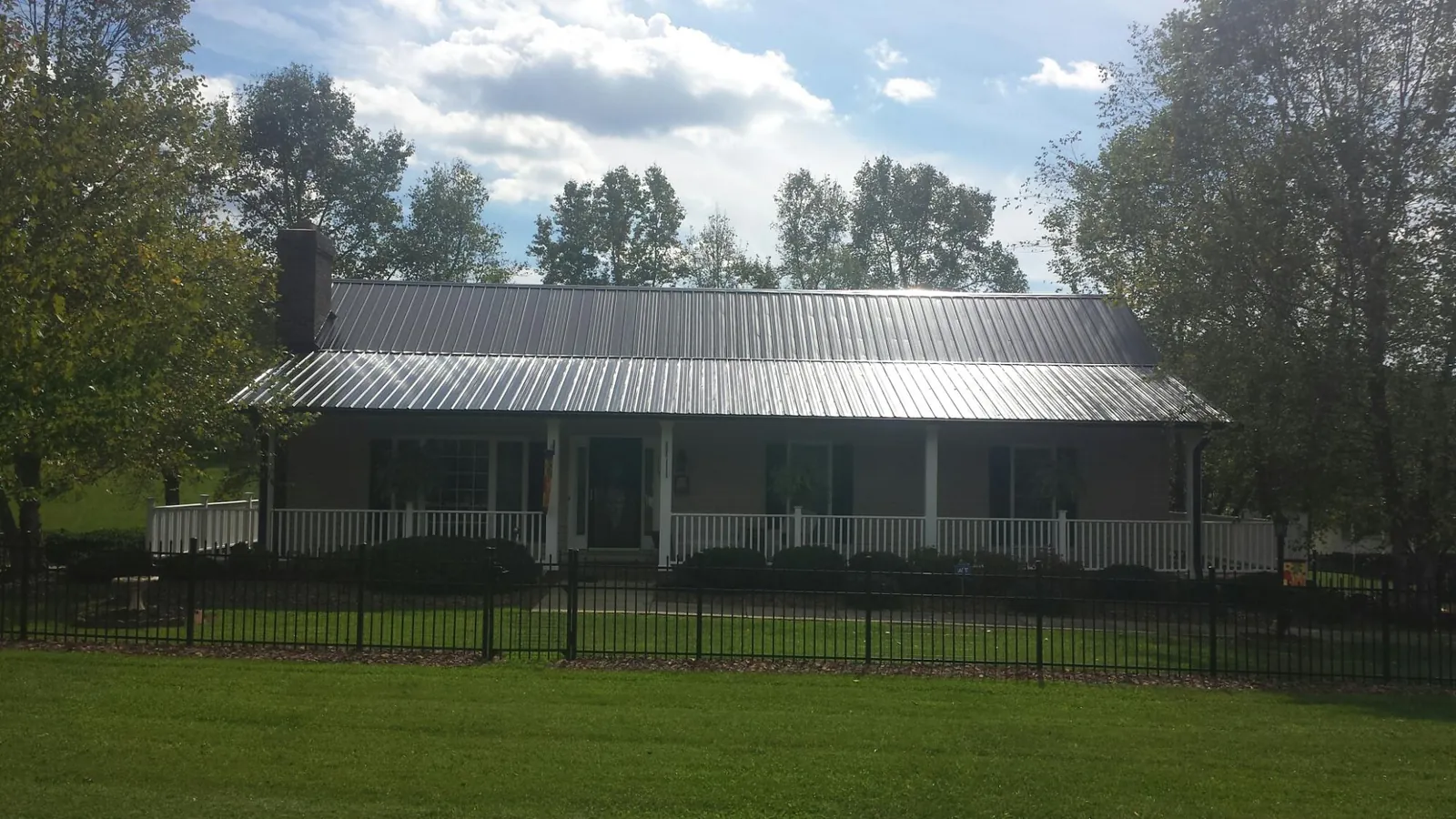 Gray metal roof on a brick ranch with a full width front porch — Gutter Guard Installation work by our crew in Packwood