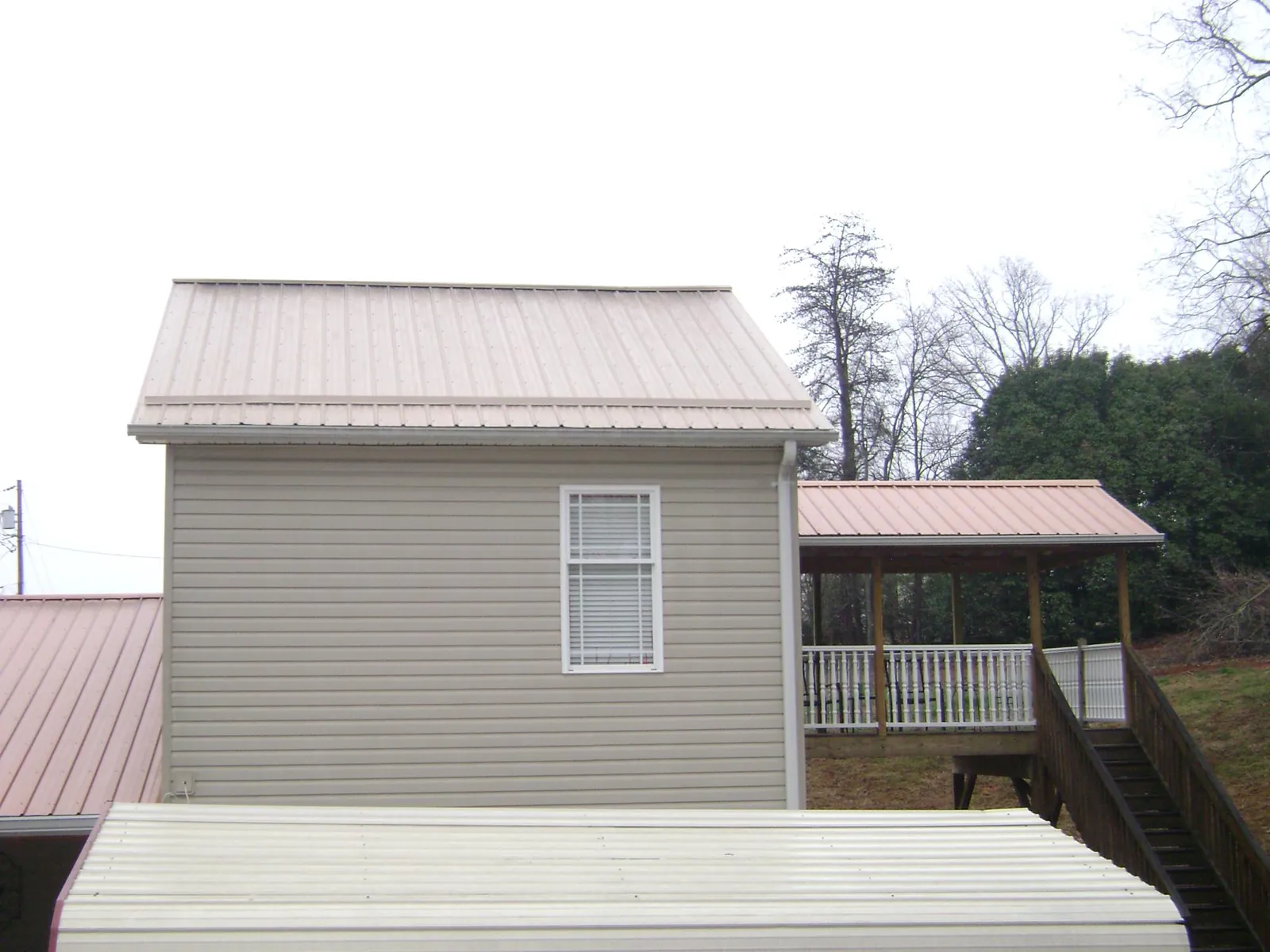 Tan metal roofs on a two story addition and attached porch, from a Roof Replacement job in Packwood