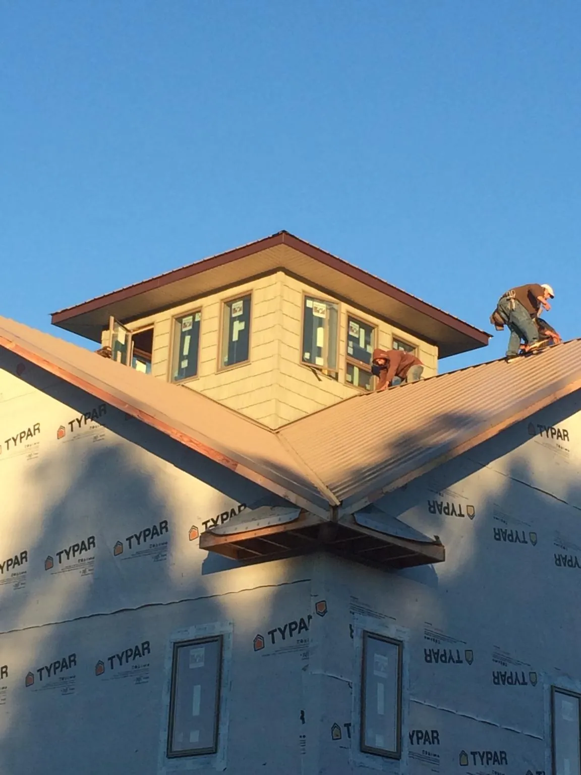 Roofers working around a rooftop cupola on a new metal roof at sunset — Roof Waterproofing in Packwood by Roofing Brothers